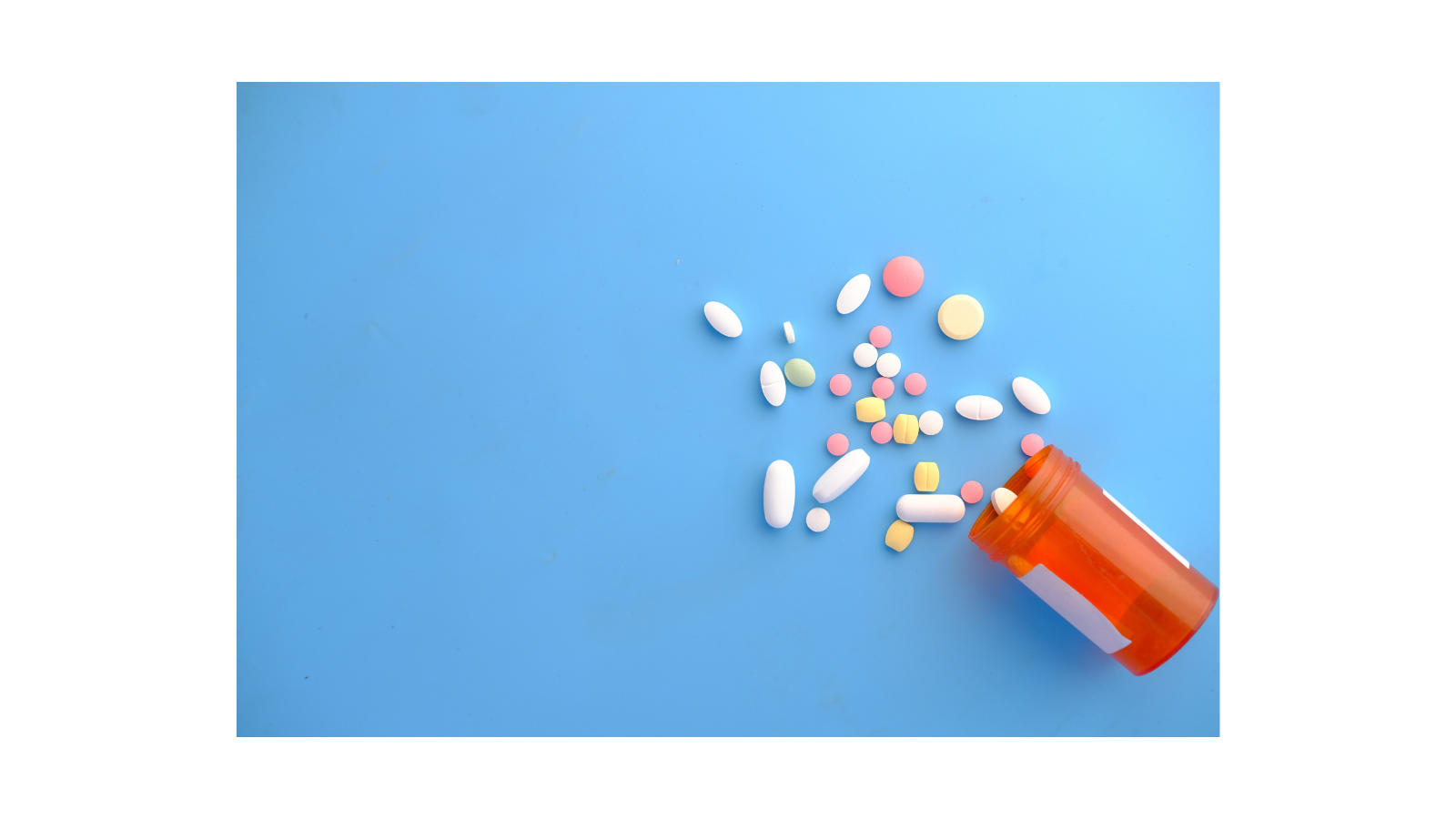 Image of pills being spilt from their container, onto a blue surface